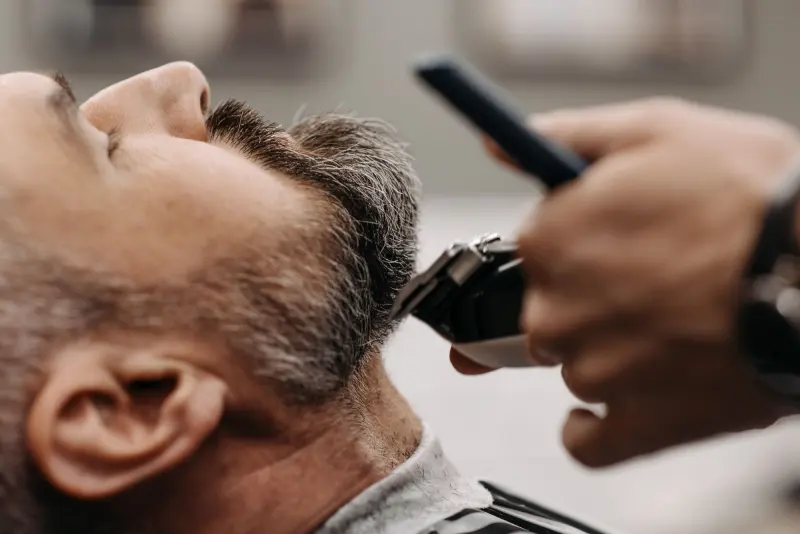 Barbero degradando la barba de un cliente con máquina